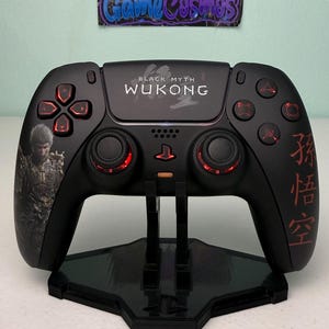 May include: A black wireless game controller featuring the text Black Myth Wukong, a graphic of a character in armor on the left grip, and red Chinese characters on the right grip. The buttons and analog sticks have red accents and lighting.