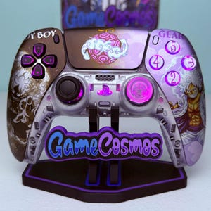 Può includere: Un controller di videogiochi personalizzato con un design viola e marrone. Il controller presenta un'illustrazione di un personaggio e il testo "Game Cosmos". I pulsanti e i joystick sono viola.