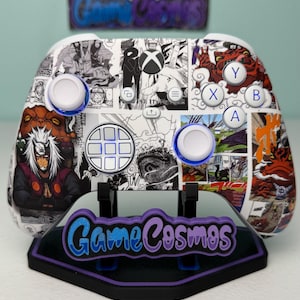 May include: An Xbox controller with a manga-style design, white buttons, and a black and purple stand. The controller's white base is covered in manga panels and character illustrations. The stand displays the text "Game Cosmos".