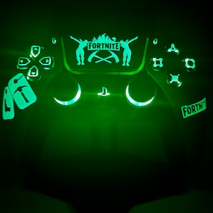 Könnte beinhalten: Ein grün beleuchteter PlayStation 5-Controller mit einem Fortnite-Logo und einem Charakterdesign auf der Oberseite. Der Controller hat ein Pickaxe-Design auf der linken Seite und ein Fortnite-Logo auf der rechten Seite.
