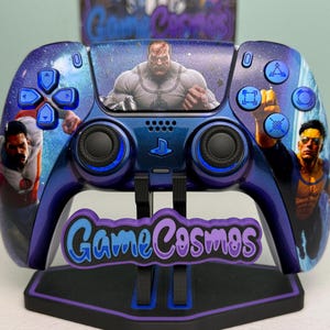 May include: A blue and purple custom game controller featuring a space-themed background with illustrations of characters from Invincible. The controller has blue buttons and joysticks, and it is displayed on a black stand with the text GameCosmos.