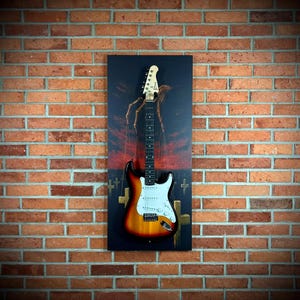 May include: A Stratocaster-style electric guitar with a sunburst finish, white pickguard, and a maple neck. The guitar is mounted on a dark canvas with a surreal image of a hand manipulating the guitar strings. The background is a brick wall.