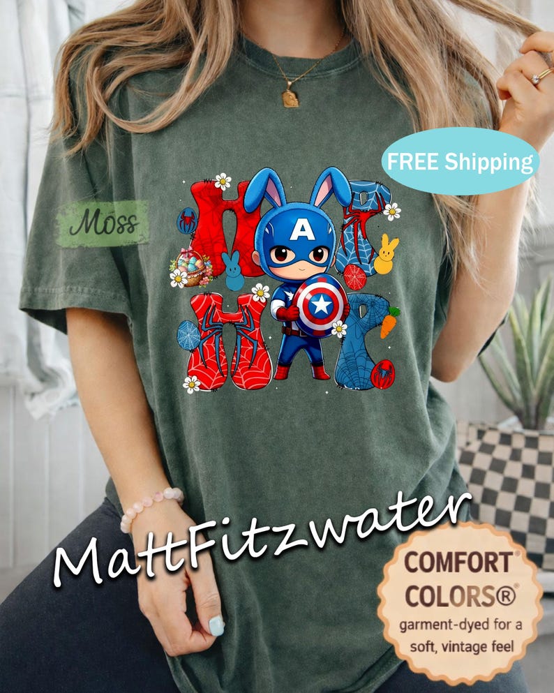 Pu&ograve; includere: T-shirt Comfort Colors verde scuro con una grafica di un coniglio supereroe e la scritta "Happy". Il design include uno scudo, orecchie da coniglio ed elementi a ragnatela. La maglietta ha un tocco morbido e vintage.