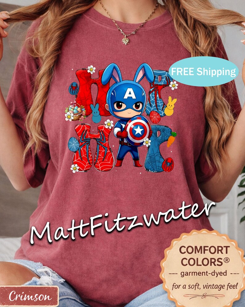 Pu&ograve; includere: Maglietta color cremisi con una grafica di un coniglio supereroe con elmetto di Capitan America e scudo. Il design include la parola "HOP" con elementi pasquali. La maglietta &egrave; tinta in capo per una sensazione morbida e vintage.