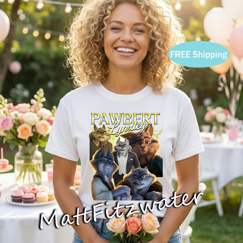 以下が含まれることがあります： 白いTシャツ。擬人化された猫のグラフィックと、黄色と緑の「PAWBERT Lynxley」の文字。Tシャツを着た人が花を持っています。背景には花とテーブルがあります。