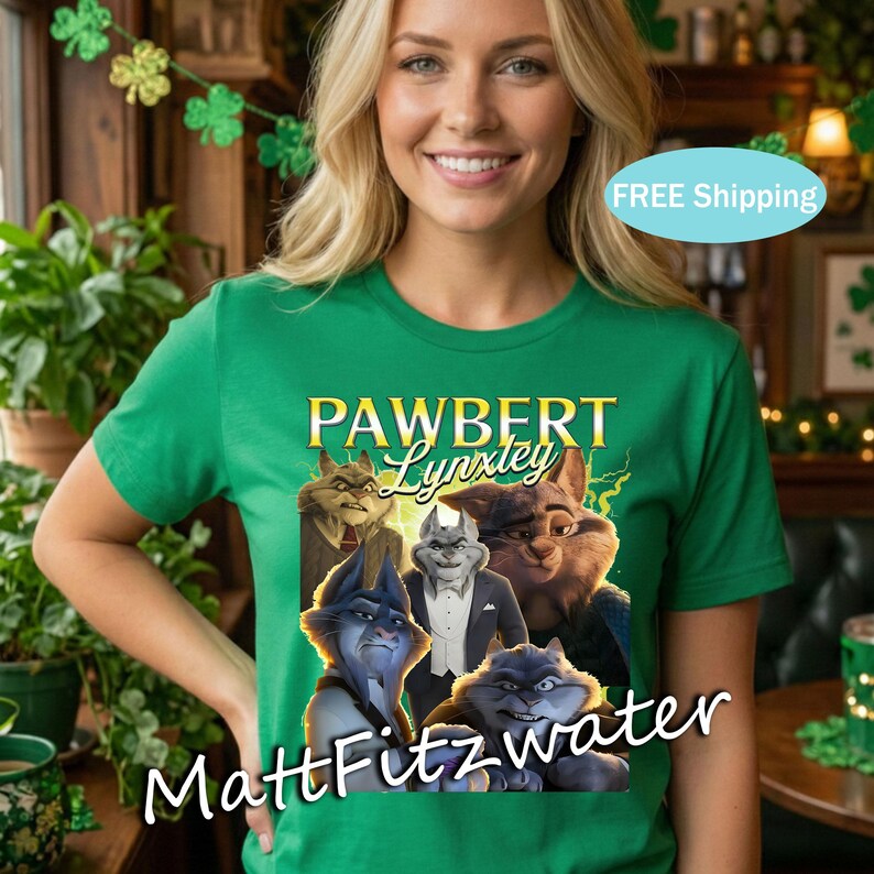 以下が含まれることがあります： 「PAWBERT Lynxley」の文字と漫画の猫のグラフィックが特徴の緑色のTシャツ。シャツの下部には「MattFitzwater」の文字も入っています。Tシャツは人が着ています。