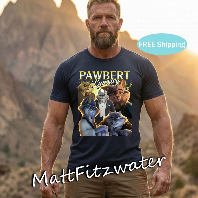 以下が含まれることがあります： 「PAWBERT Lynxley」の文字と漫画の猫のグラフィックがプリントされたネイビーブルーのTシャツ。Tシャツは、あごひげを生やした人が着ており、背景はぼやけた屋外です。