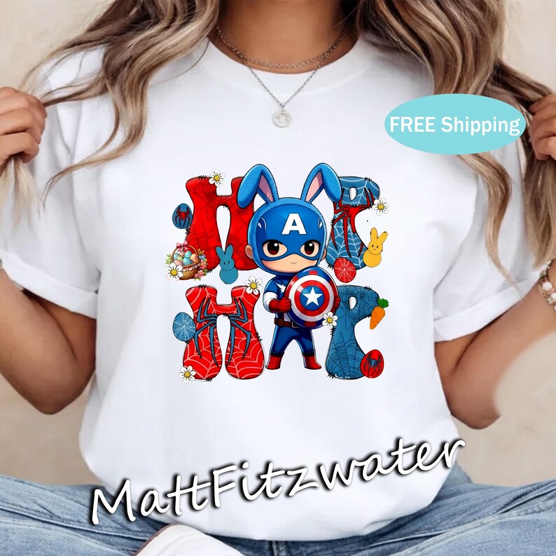 Pu&ograve; includere: T-shirt bianca con una grafica colorata di un personaggio di supereroe con orecchie da coniglio che tiene uno scudo. La parola "HOP" &egrave; scritta con lettere e disegni a tema pasquale. La maglietta ha scollo tondo e maniche corte.