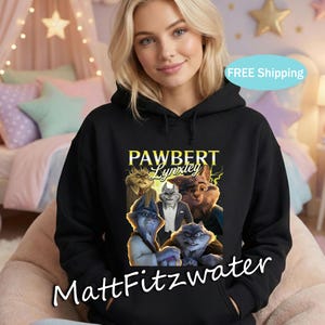 以下が含まれることがあります： 黒いフード付きスウェットシャツ。擬人化されたオオヤマネコのキャラクターのグラフィックと、黄色の「PAWBERT Lynxley」の文字が特徴です。スウェットシャツには、白い文字で「MattFitzwater」も書かれています。