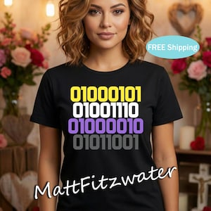 May include: Black t-shirt featuring binary code in yellow, white, purple, and grey. The text reads "01000101 01001110 01000010 01011001". The shirt also has the name "MattFitzwater" printed at the bottom.