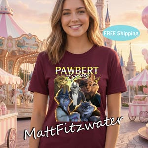 以下が含まれることがあります： 「PAWBERT Lynxley」の文字と擬人化された猫のグラフィックが特徴の、マルーン色のTシャツ。クルーネックと半袖のデザインです。アーティスト名「MattFitzwater」がシャツの下部にプリントされています。