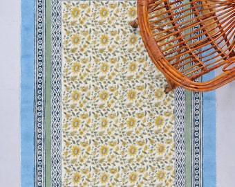 Könnte beinhalten: Ein rechteckiger Teppich mit einem zentralen Muster aus gelben Blumen und grünen Blättern auf cremefarbenem Grund, umrahmt von einer grünen Bordüre, einem dunkelblauen geometrischen Rand und einem breiten hellblauen Außenrand mit Fransen.