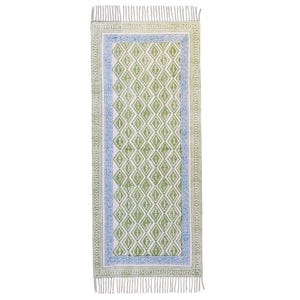 Puede incluir: Una alfombra rectangular de color blanco roto con un patrón de diamantes repetido en verde y blanco. La alfombra tiene un borde azul y flecos en los extremos. La alfombra mide aproximadamente 152 cm de largo y 61 cm de ancho.