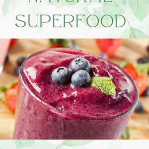 Puede incluir: Un primer plano de un batido prebi&oacute;tico hecho con ar&aacute;ndanos y adornado con menta fresca. El batido est&aacute; en un vaso transparente y es de un color morado vibrante. El texto "NATURAL SUPERFOOD" est&aacute; en la parte superior de la imagen y "prebiotic smoothie" en la parte inferior.