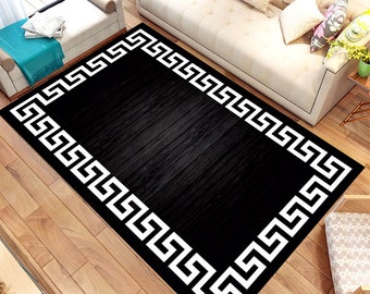 May include: Black and white area rug with a geometric Greek key border design. The rug has a black background and a white border.