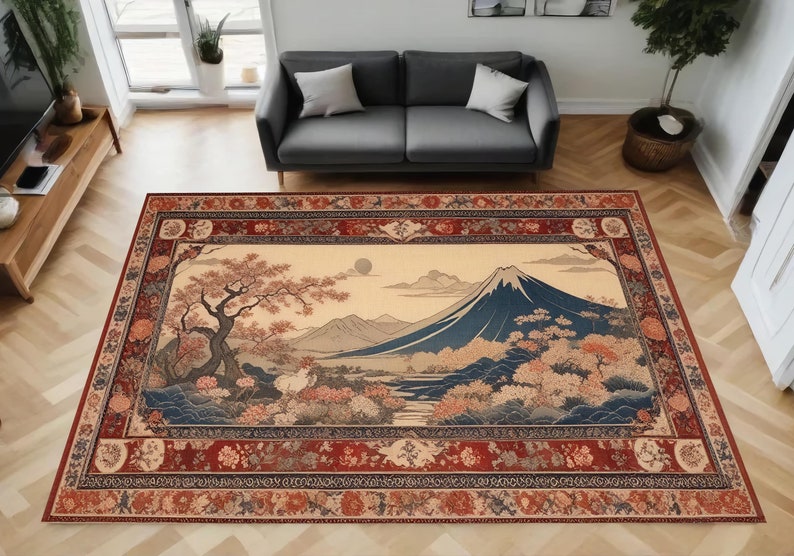 May include: A traditional Japanese-style rug with a beige background and a detailed illustration of Mount Fuji, a cherry blossom tree, and other floral elements. The rug has a red, brown, and cream-colored border with intricate floral patterns.