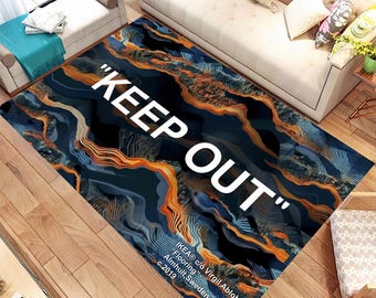 May include: A black and blue rug with orange and white abstract lines. The rug has the text "KEEP OUT" in white letters.