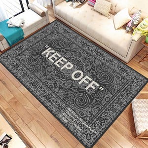 May include: A black and white patterned rug with the text "KEEP OFF" in white lettering. The rug has a traditional design with intricate details. The text "IKEA.co/VirgilAbloh Flooring" is also visible in the bottom right corner.