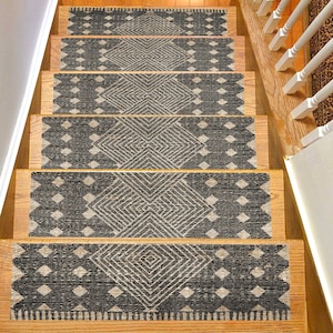 Può includere: Gradini con un design geometrico in nero e beige. I gradini sono rettangolari e presentano un motivo ripetuto di diamanti e linee. I gradini sono posizionati su scale di legno.