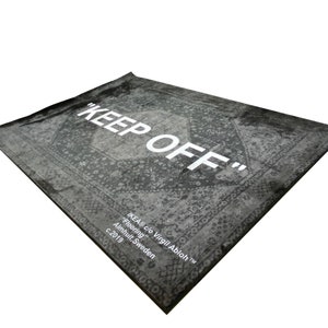 May include: A black and white rug with a vintage pattern and the text "KEEP OFF" in white. The rug is labeled "IKEA&reg; c/o Virgil Abloh&trade;" and "Flooring" with the location "Almhult, Sweden" and the year "c. 2019".