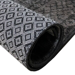 May include: Close-up of a black and white patterned rug rolled up, showing the black edging and the geometric design.