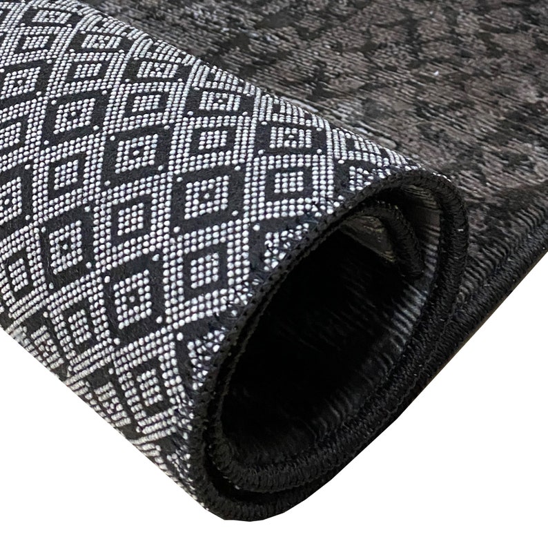 May include: Close-up of a black and white patterned rug rolled up, showing the black edging and the geometric design.