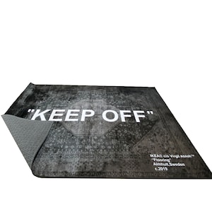 May include: A black and white rug with a vintage pattern and the text "KEEP OFF" in white. The rug is made by IKEA in collaboration with Virgil Abloh and is labeled "Flooring" with the location Almhult, Sweden and the year 2019.