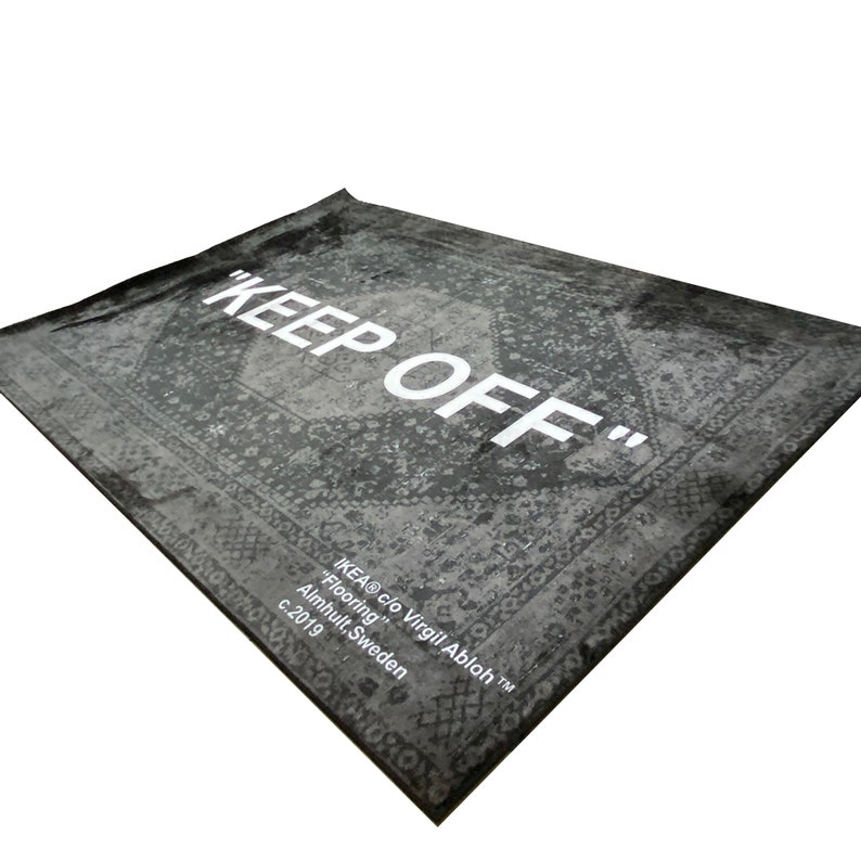 May include: A black and white rug with a vintage pattern and the text "KEEP OFF" in white. The rug is labeled "IKEA&reg; c/o Virgil Abloh&trade;" and "Flooring" with the location "Almhult, Sweden" and the year "c. 2019".
