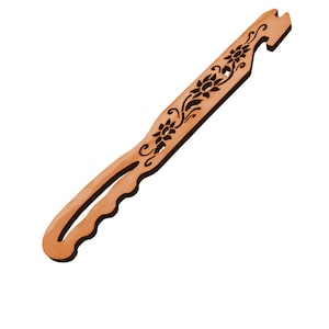 May include: A wooden tool with a handle and a floral design. The tool is light brown with a series of carved flowers and swirls. The handle has a curved shape with finger grooves for grip. The end has a notched design.