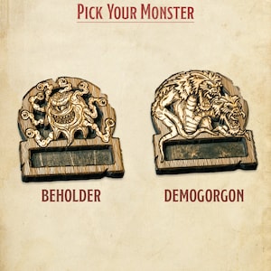 May include: Two wooden plaques featuring monster illustrations. The plaque on the left depicts a beholder with a central eye and numerous tentacles. The plaque on the right shows a demon with a dragon-like head and a snarling face. Both plaques have a blank space for text. The text below the plaques reads "BEHOLDER" and "DEMOGORGON".