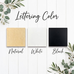 以下が含まれることがあります： Lettering Colorというタイトルのカラーチャートには、Natural、White、Blackとラベル付けされた3つの正方形のサンプルが表示されています。Naturalは明るい木目調、Whiteは無地の白、Blackは無地の黒い正方形です。