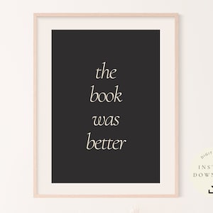 Puede incluir: Una impresión de arte de cita imprimible en blanco y negro con el texto "the book was better" en una fuente cursiva blanca. La impresión está enmarcada en un marco de madera claro.