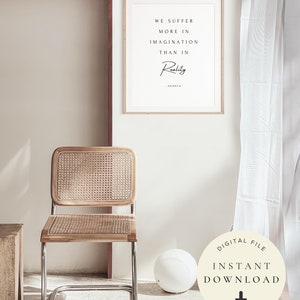 Pu&ograve; includere: Un poster stampabile con una citazione su sfondo bianco e testo nero. La citazione recita "We suffer more in imagination than in reality - Seneca". Il poster &egrave; incorniciato in una cornice di legno chiaro e appeso a una parete bianca. Una sedia in vimini e una palla bianca sono in primo piano.