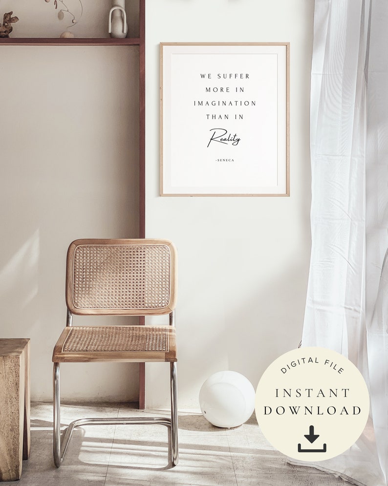 Pu&ograve; includere: Un poster stampabile con una citazione su sfondo bianco e testo nero. La citazione recita "We suffer more in imagination than in reality - Seneca". Il poster &egrave; incorniciato in una cornice di legno chiaro e appeso a una parete bianca. Una sedia in vimini e una palla bianca sono in primo piano.