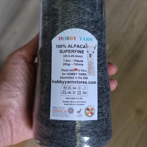 Pode incluir: Um novelo de l&atilde; de alpaca 100% superfina cinza-escura da Hobby Yarn. O r&oacute;tulo especifica 200gr, 700mts, 7.0oz, 764yds e inclui instru&ccedil;&otilde;es de cuidado, tamanho de agulha 3,25-3,75mm e tamanho de agulha de croch&ecirc; 3,5-4,0mm.