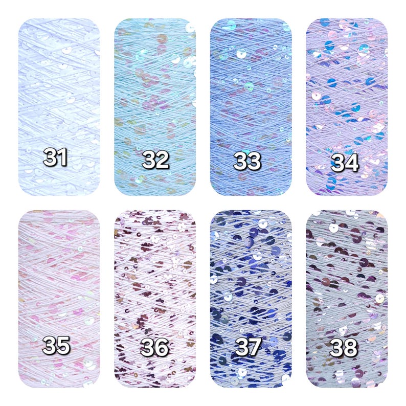 May include: Eight vertical spools of yarn labeled 31 through 38, each featuring a distinct color palette with integrated reflective sequins. The collection includes shades of white, light blue, medium blue, lavender, pink, and grey with varied sequin densities.