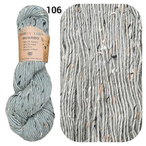 May include: A skein of Hobby Yarn Huambo in color 106. The yarn is a light blue-grey with flecks of black, white, and brown. The label indicates it's 50% FS Alpaca, 20% Donegal, and 30% Fine Highland Wool. The skein weighs 3.5 oz and is 175 yards long.