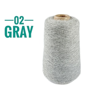 Pode incluir: Um cone grande de fio cinza-claro com uma apar&ecirc;ncia felpuda e texturizada. O topo do cone apresenta um n&uacute;cleo de papel&atilde;o marrom. &Agrave; esquerda do cone de fio, o texto 02 GRAY est&aacute; impresso em uma fonte sem serifa verde-azulado com linhas.