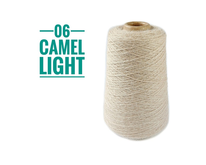 Pode incluir: Um carretel c&ocirc;nico de fio bege claro com textura felpuda. &Agrave; esquerda do carretel, o texto 06 CAMEL LIGHT est&aacute; impresso em verde-azulado, entre duas linhas horizontais. O fio est&aacute; enrolado firmemente em torno de um n&uacute;cleo de papel&atilde;o.