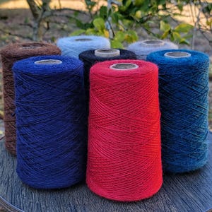 Pode incluir: Uma cole&ccedil;&atilde;o de sete cones de fio em v&aacute;rias cores, incluindo vermelho brilhante, azul marinho profundo, castanho escuro, preto, azul claro e cinzento. Cada cone &eacute; enrolado com fio fino e texturizado e apresenta um n&uacute;cleo central de cart&atilde;o.