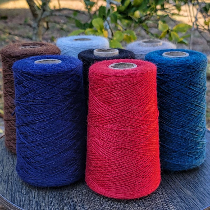 Pode incluir: Uma cole&ccedil;&atilde;o de sete cones de fio em v&aacute;rias cores, incluindo vermelho brilhante, azul marinho profundo, castanho escuro, preto, azul claro e cinzento. Cada cone &eacute; enrolado com fio fino e texturizado e apresenta um n&uacute;cleo central de cart&atilde;o.