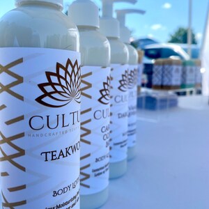 May include: Four bottles of body lotion with white labels and gold lettering. The labels feature a lotus flower design and the text "CULTURE HANDCRAFTED SOAP & TEAKWOOD BODY LOTION Luxurious Moisturizing Body Lotion with Shea Butter and Aloe 8.0 fl oz".