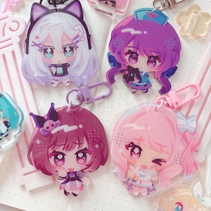 May include: Four acrylic keychains featuring chibi-style anime characters with colorful hair and outfits, each attached to a metal or plastic clasp. The designs include a white-haired character with cat ears, a purple-haired nurse, a dark pink-haired figure, and a light pink-haired character with a bow.