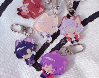 May include: A collection of colorful anime-style character keychains. Each keychain features a unique character design with vibrant colors, attached to a silver-colored metal clasp. The keychains are in various colors, including red, pink, purple, and blue.