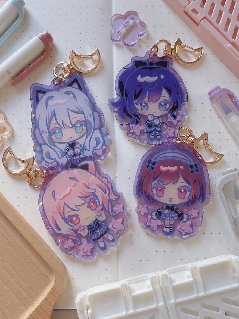Puede incluir: Cuatro llaveros de personajes de estilo anime con herrajes dorados. Los llaveros presentan personajes con diferentes colores de cabello: blanco, morado, rosa y rojo. Cada personaje est&aacute; rodeado de detalles en forma de estrella y tiene un dise&ntilde;o de orejas de gato o lazo.