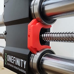 May include: Close-up of a black machine component with the text "ONEFINITY" and the tagline "One Machine Infinite Possibilities." A red bracket is attached to a silver rod and a threaded rod. The machine has silver bearings.