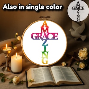 May include: A rainbow cross with the word "GRACE" across the centre and the word "AMAZING" vertically down the centre. The cross is in a wooden embroidery hoop and is sitting on a closed book with a white dove and flowers in the background.