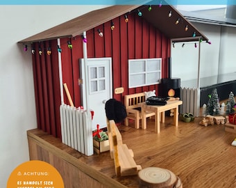 May include: A red wooden miniature house with a white picket fence and a small wooden table and chairs on the porch. The house has a white door and windows and is decorated with string lights. The text "ACHTUNG: ES HANDELT SICH HIERBEI UM EINE DATEI. DIES IST NUR EIN BEISPIELBILD." is visible on the bottom left of the image.