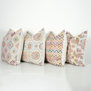 Può includere: Quattro cuscini decorativi con diversi motivi. I cuscini sono tutti bianchi con motivi colorati. I motivi includono un motivo geometrico, un motivo floreale, un motivo chevron e un motivo paisley.