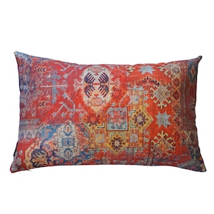 Op de afbeelding: Rood, blauw en geel gepatroneerd kussen met een geometrisch ontwerp.